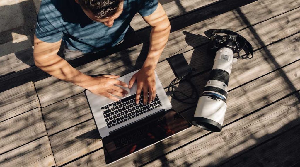 Fotógrafo conectándose con un portátil a una cámara Olympus con el nuevo teleobjetivo.