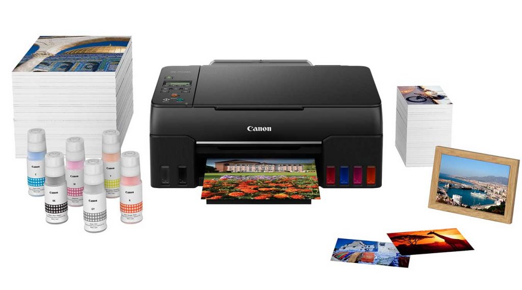 Bodegón con la impresora Pixma G650, botellas de tinta, papel y fotografías impresas.